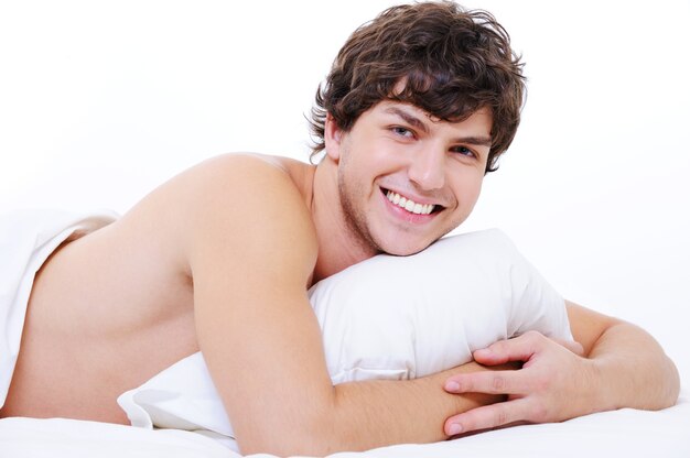 침대에 누워 행복 웃는 젊은 아름다운 남자의 초상화
