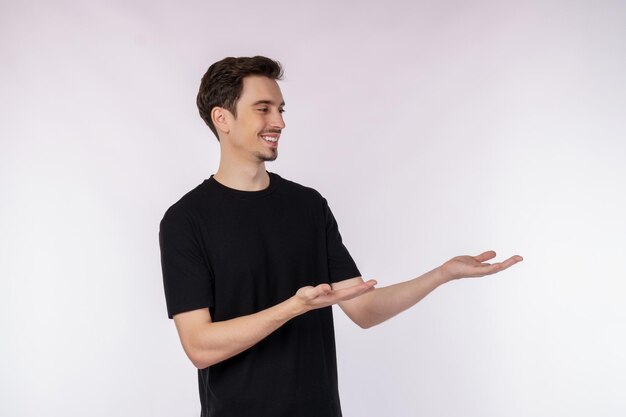 Portrait of happy smiling young man presenting and showing your text or product isolated on white background