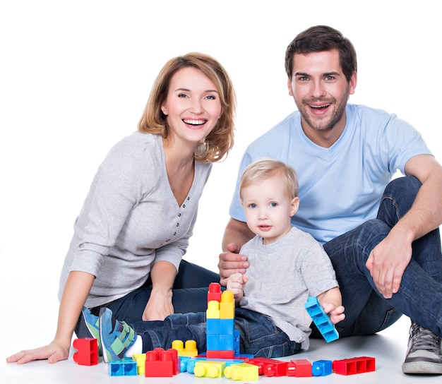 Portrait of happy smiling young parents playing with a baby - isolated on white