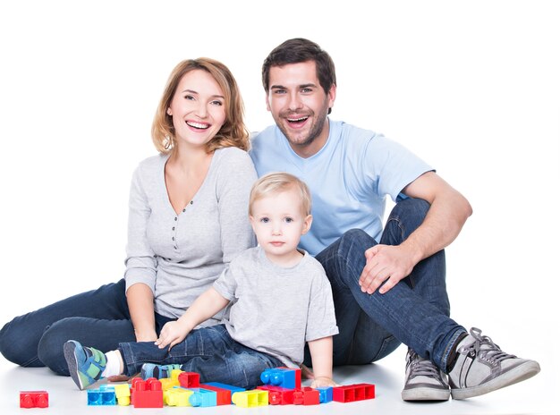 Портрет счастливых улыбающихся молодых родителей, играющих с ребенком - изолированные на белом