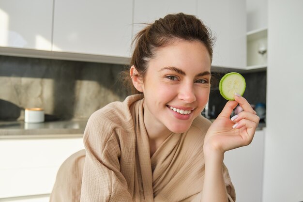 Portrait of happy smiling young woman in the kitchen cooking chopping zucchini holding vegetables