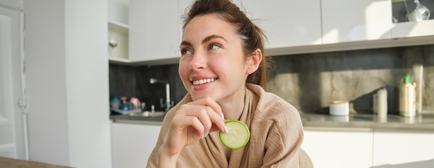 Foto gratuita ritratto di giovane donna sorridente felice in cucina che cucina tagliando le zucchine che tengono le verdure