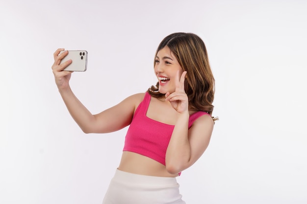흰색 배경 위에 스마트폰으로 웃고 있는 행복한 젊은 여성 셀카의 초상화