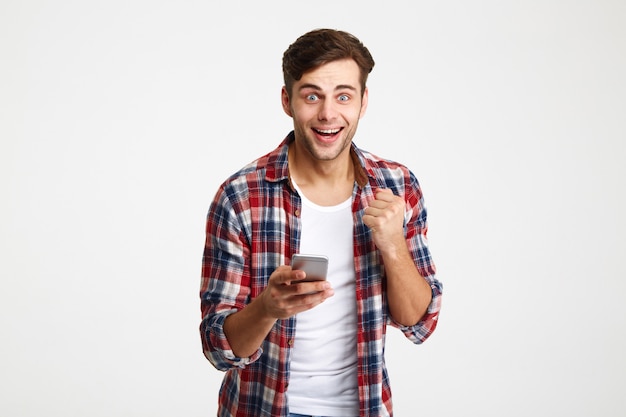 Portrait of a happy surprised man looking holding mobile phone