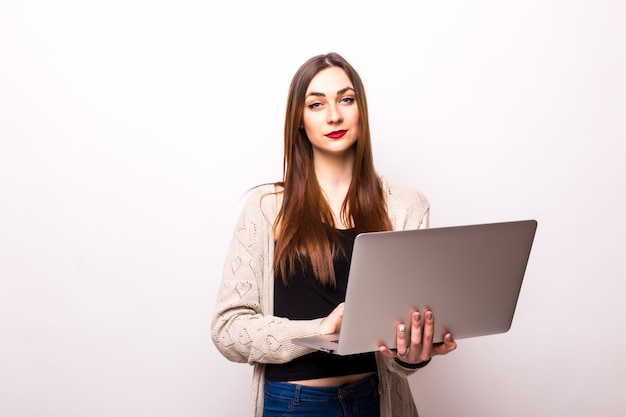 Портрет счастливой удивленной женщины, стоящей с ноутбуком на сером