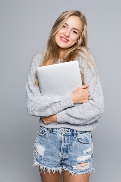 Portrait of happy surprised woman standing with laptop isolated on gray background