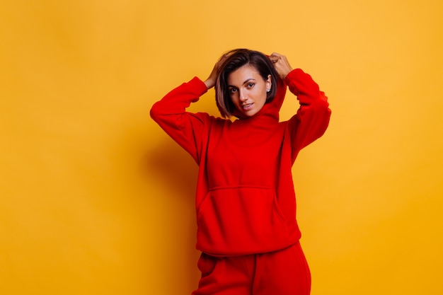 Portrait of happy tanned fit woman wearing trendy warm red fleece hoodie and pants, getting ready for cold winter
