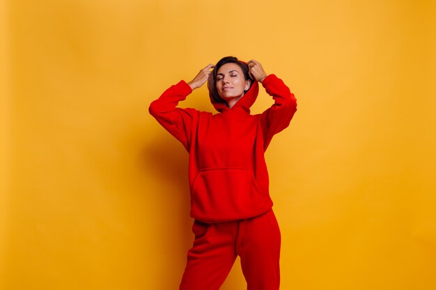 Portrait of happy tanned fit woman wearing trendy warm red fleece hoodie and pants