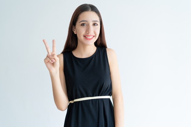 Portrait of happy teenage girl showing victory gesture