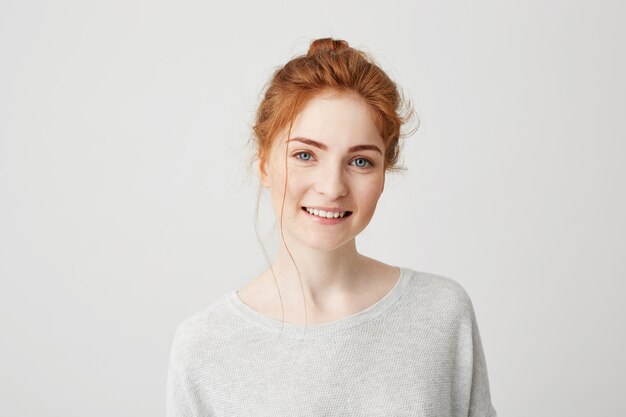 Portrait of happy tender ginger girl with blue eyes and freckles smiling .