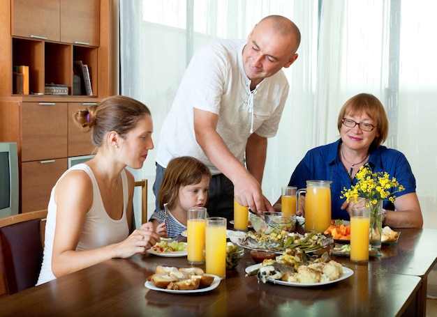 Портрет счастливой семьи трех поколений, позирует вместе над здоровым столом