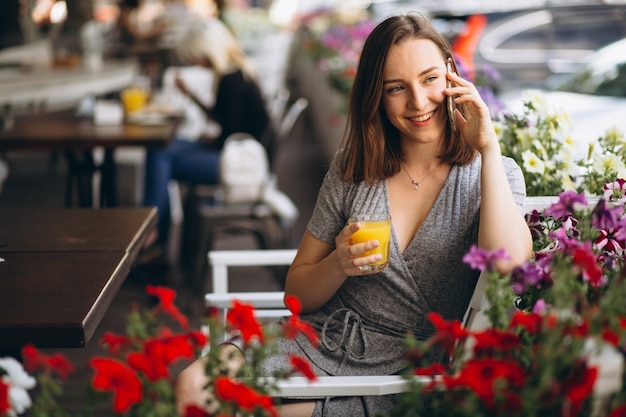 Portrait of a happy woman in a cafe with phone and juice