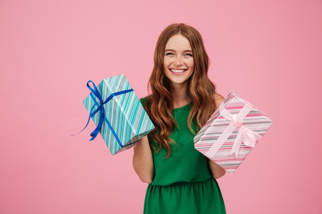 Portrait of a happy woman in dress holding present boxes