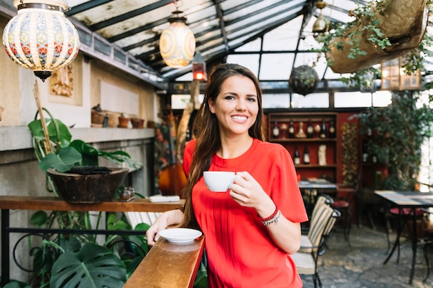 Foto gratuita ritratto di una donna felice che beve tazza di caffè