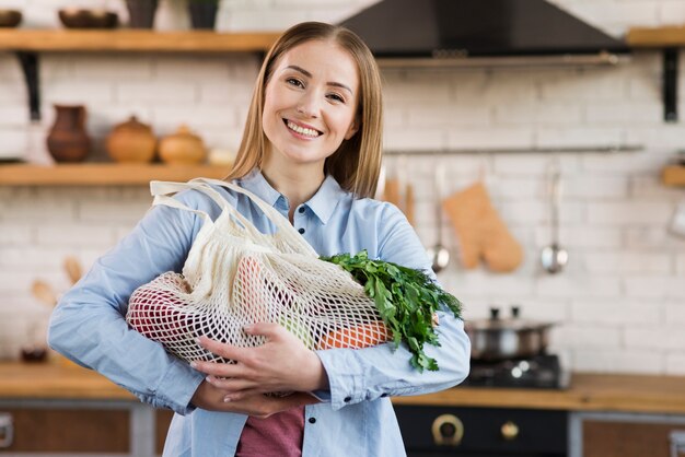 Портрет счастливой женщины, держащей сумки с органическими овощами