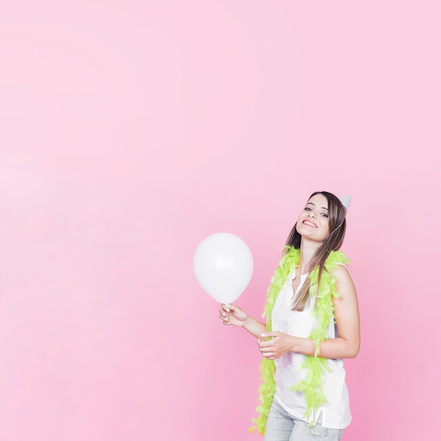ピンクの背景に白い風船を保持している幸せな女性の肖像