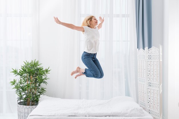 침대에서 점프하는 행복 한 여자의 초상화