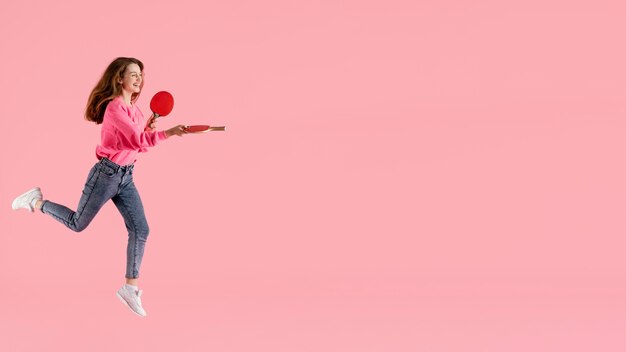 Портрет счастливая женщина прыгает с веслом для пинг-понга