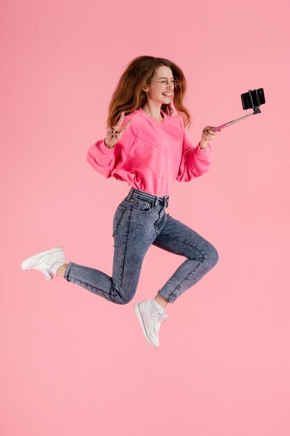 Selfie 막대기로 점프 세로 행복 한 여자