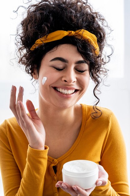 Portrait of happy woman laughing and playing with moisturizer