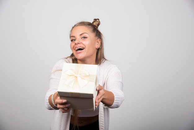 Portrait of happy woman offering white gift box.