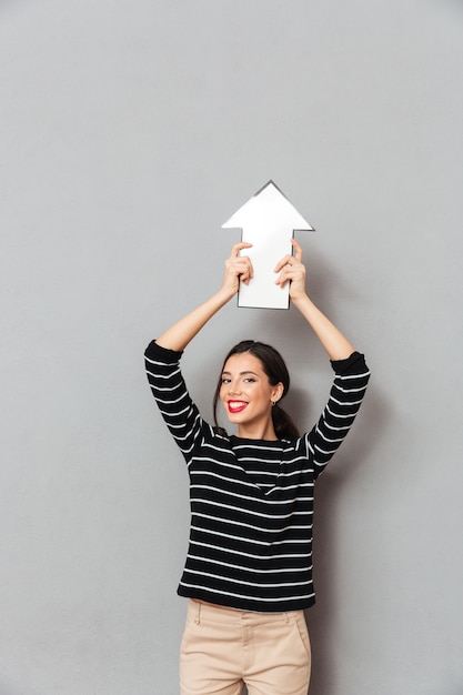 Free photo portrait of a happy woman pointing up with an arrow