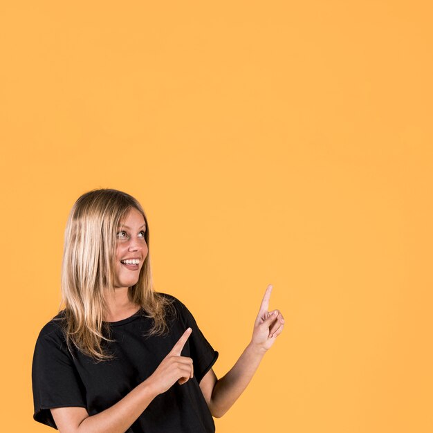 Portrait of happy woman pointing upward direction and looking up