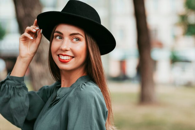 Портрет счастливой женщины, позирующей в черной шляпе