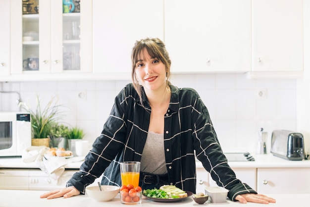 Free photo portrait of a happy woman standing in kitchen