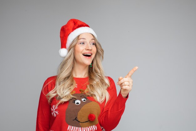 Portrait of happy woman in sweater and cristmas hat is delighted with something