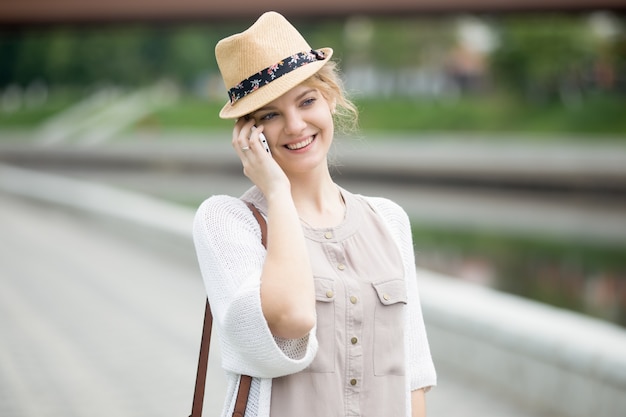 Portrait of happy woman talking on smartphone while walking