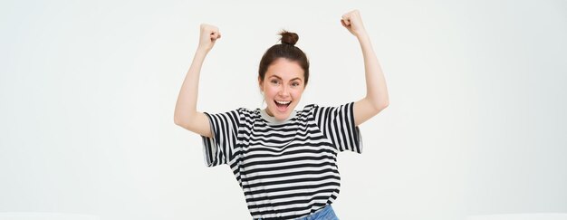 Portrait of happy woman winning celebrating victory rooting for team triumphing standing over white