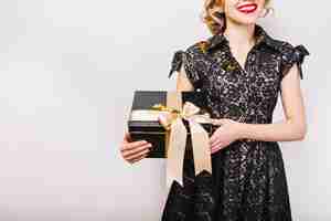 Free photo portrait happy woman with black gift box in hand, red lips, black dress, smile.