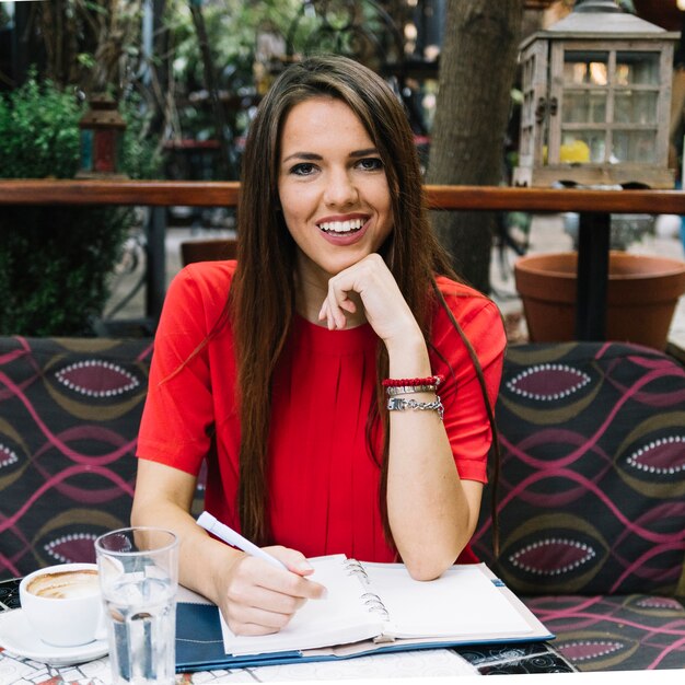 Free photo portrait of a happy woman with diary on desk