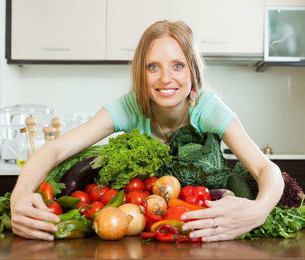 Portrait of happy woman with heap of vegetables