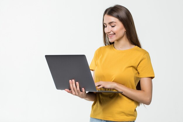 Портрет счастливая женщина работает на ноутбуке, изолированных на белой стене