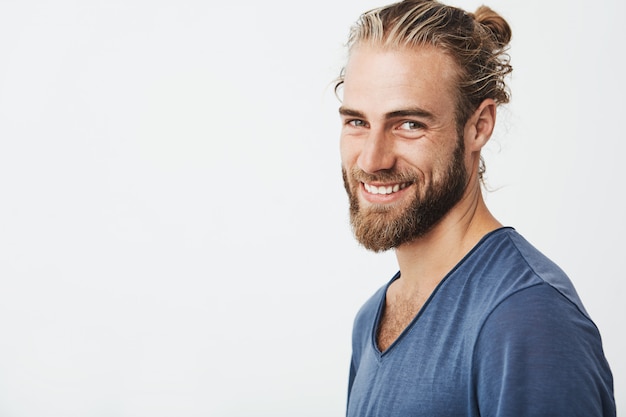 Portrait of happy young bearded guy with fashionable hairstyle and beard