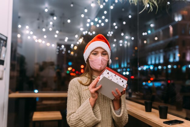 Portrait happy young beautiful woman hold gift box and smile in cafe