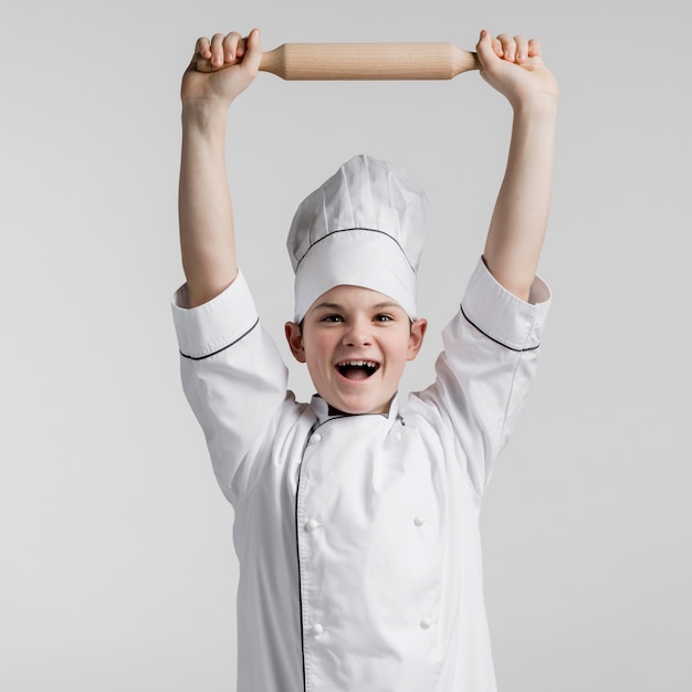 Free photo portrait of happy young boy holding rolling pin