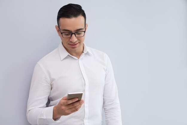 Portrait of happy young businessman reading or texting message