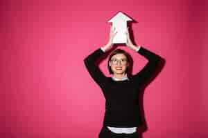 Free photo portrait of a happy young businesswoman holding paper arrow sign