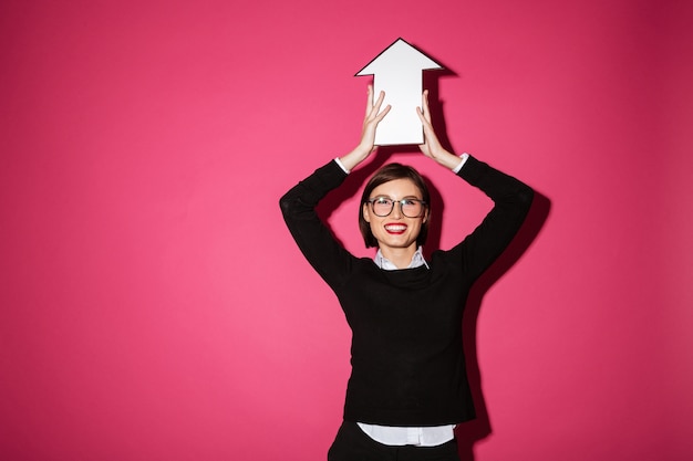 Portrait of a happy young businesswoman holding paper arrow sign