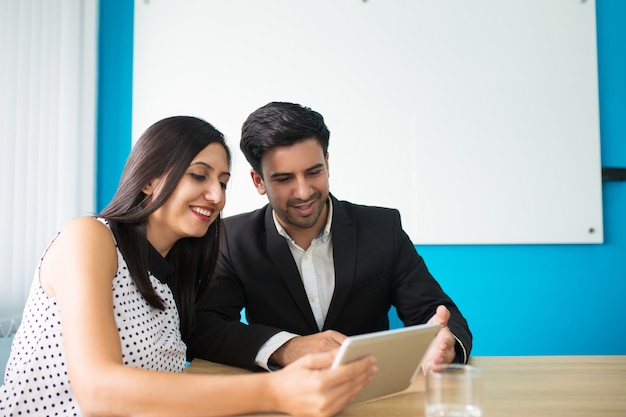 Portrait of happy young colleagues using digital tablet