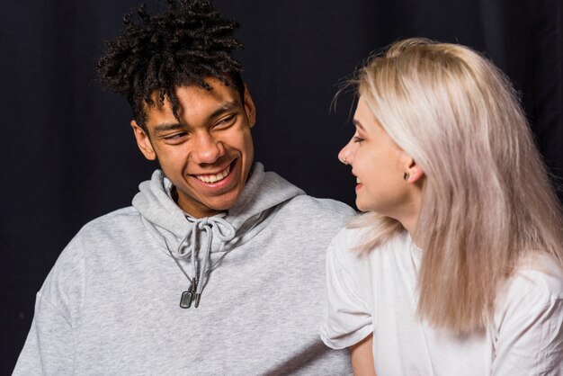 Portrait of happy young couple against black background