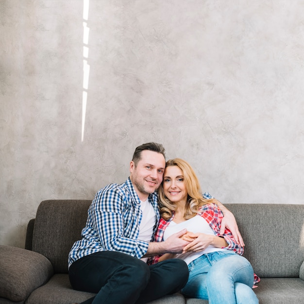 Portrait of happy young couple sitting on sofa looking at camera