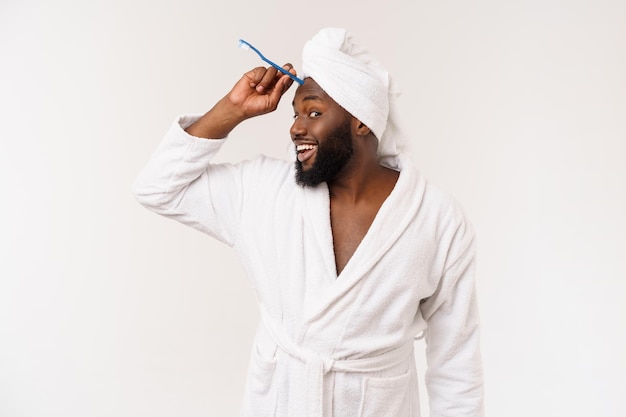 Portrait of a happy young darkanm brushing his teeth with black toothpaste on a white background