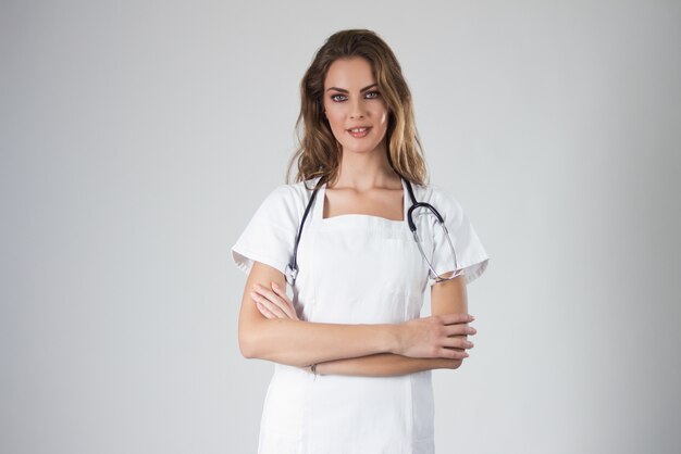 Портрет счастливый молодой врач женщина стоял, изолированных на белом фоне.