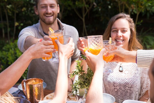 Portrait of happy young friends toasting juice outdoors