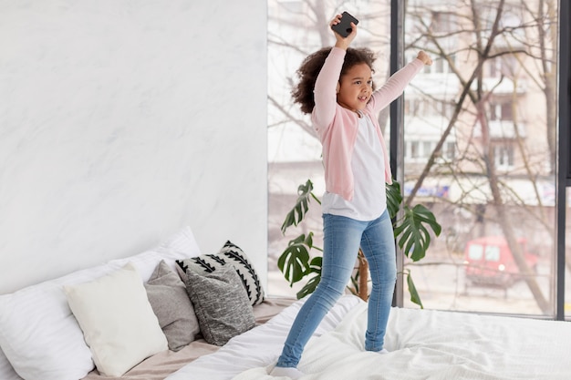 Free photo portrait of happy young girl jumping in bed
