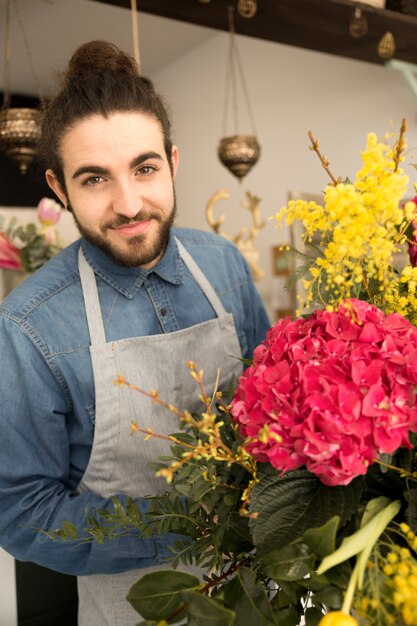 花の花束を持つ幸せな若い男性花屋の肖像画